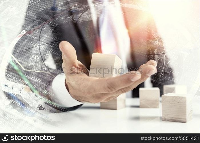 He is building his business. Close view of businessman making pyramid with empty wooden cubes
