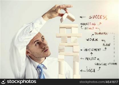 He is building his business. Young businessman making pyramid with empty wooden cubes