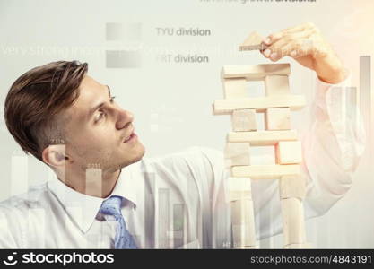 He is building his business. Young businessman making pyramid with empty wooden cubes