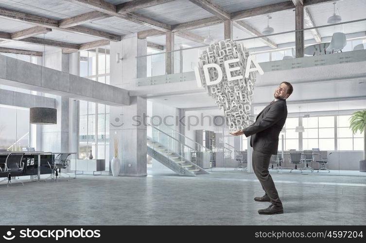 He is carrying out an idea. Elegant businessman in modern office with huge bulb in hands