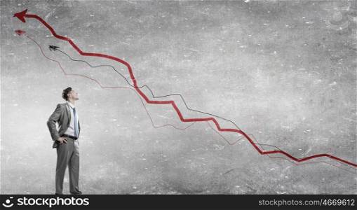 He is confident in his success. Confident businessman with arms on waist and red growing arrow graph