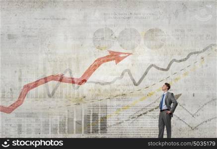 He is confident in his success. Confident businessman with arms on waist and red growing arrow graph