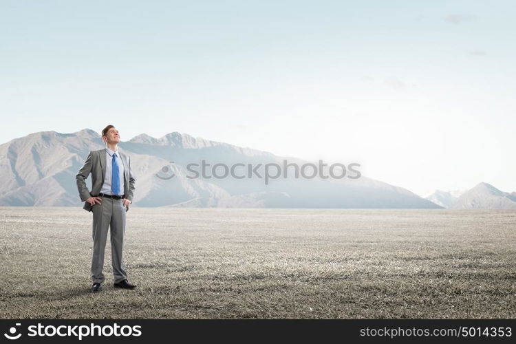 He is confident in his success. Young confident businessman with arms on waist outdoor