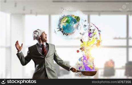He is cooking something special. Young man in business suit and cook hat holding pan. Elements of this image are furnished by NASA