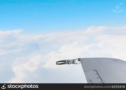 He is flying high. Young businessman hanging on edge of airplane wing