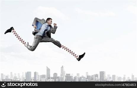 He is making giant steps. Businessman in suit running with big springs on feet