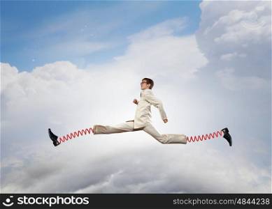 He is making giant steps. Businessman in suit running with big springs on feet