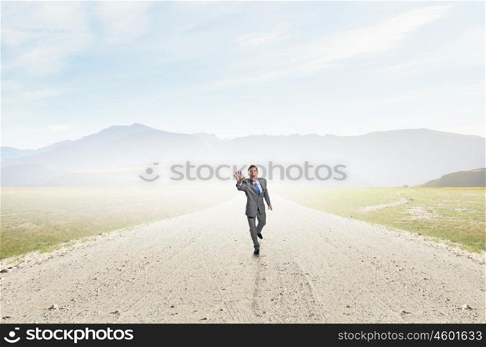 He is ready to compete. Young businessman in suit running on asphalt road