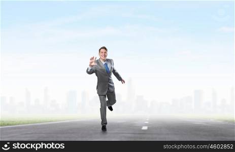 He is ready to compete. Young businessman in suit running on asphalt road
