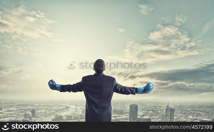 He is ready to fight for success. Young businessman in boxing gloves on dark background