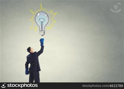 He is ready to fight for success. Young businessman in boxing gloves punch idea bulb