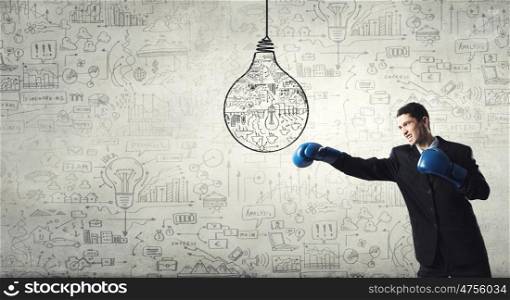 He is ready to fight for success. Young businessman in boxing gloves punching idea bulb