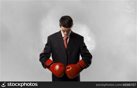 He is ready to fight for success. Young businessman in red boxing gloves on white background