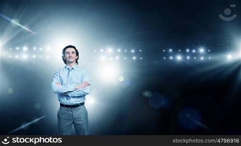 He is ready to performe. Businessman with arms crossed on chest standing in lights of stage
