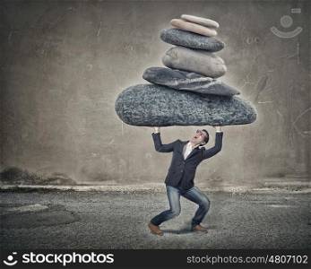 He is strong enough to do it. Young strong man holding huge stone above head