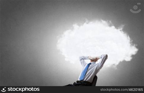 He is up in the clouds. Young businessman sitting in chair and cloud instead of head