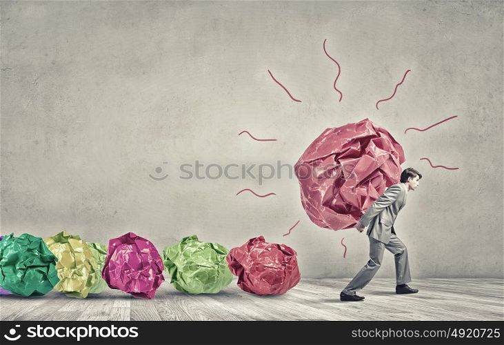 He is working hard on his new idea. Businessman carrying with effort big crumpled ball of paper as creativity sign