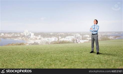 He is young professional. Confident businessman outdoor standing with arms crossed