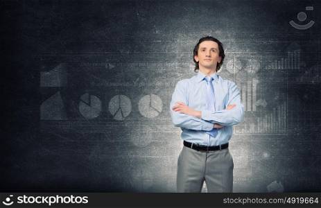 He is young professional. Young confident businessman with arms crossed on chest against concrete background
