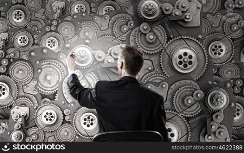 He possesses constructive thinking. Young relaxed businessman sitting in chair and touching gears mechanism