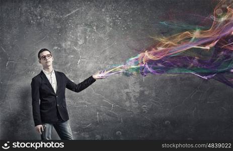 He possesses creative thinking. Young man in red glasses and colorful lights from his hand