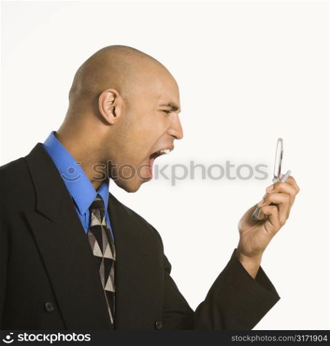Head and shoulder portrait of African American man in suit yelling at cellphone.