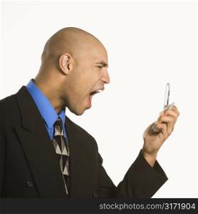 Head and shoulder portrait of African American man in suit yelling at cellphone.