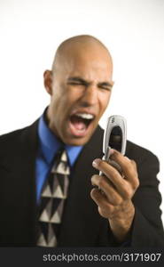 Head and shoulder portrait of African American man in suit yelling at cellphone.