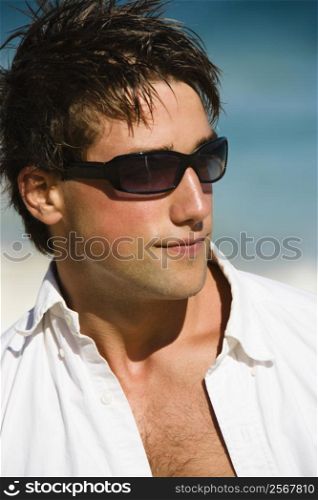Head and shoulder portrait of attractive man wearing sunglasses on Maui, Hawaii beach.