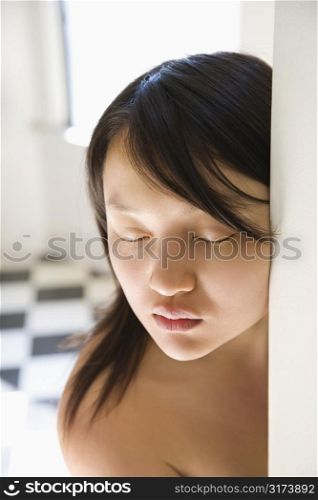 Head and shoulder portrait of bare pretty young Asian woman with eyes closed.