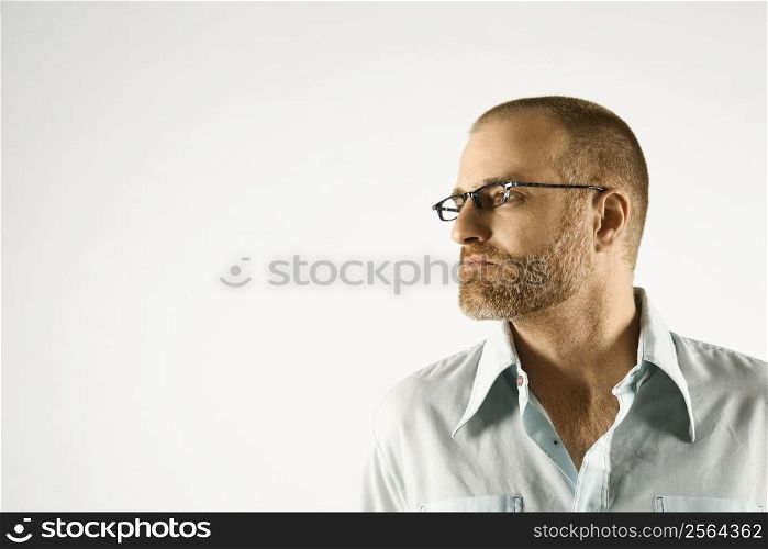 Head and shoulder portrait of Caucasian man looking to side against white background.