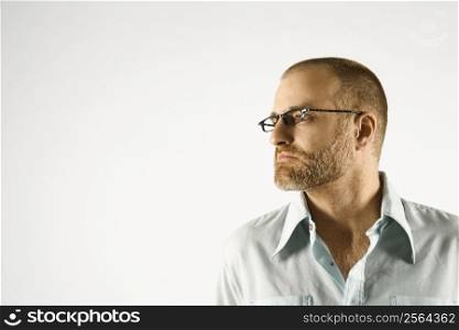 Head and shoulder portrait of Caucasian man looking to side against white background.