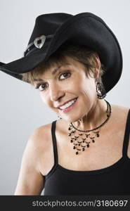 Head and shoulder portrait of pretty Caucasian woman smiling and wearing cowboy hat.