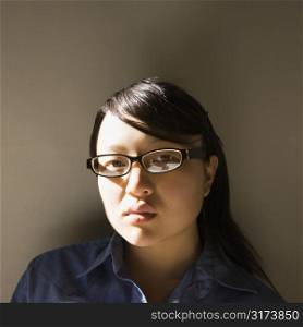 Head and shoulder portrait of pretty young Asian woman wearing eyeglasses.