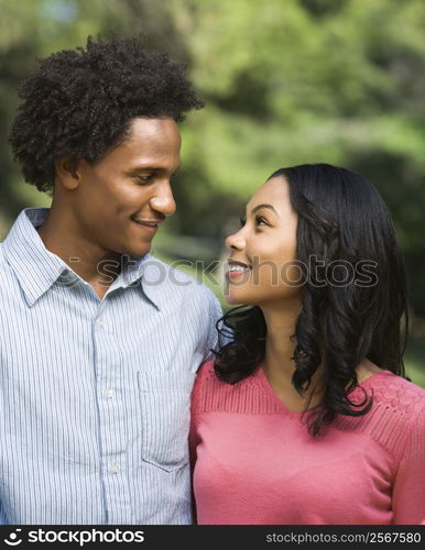 Head and shoulder portrait of smiling couple looking into eachother&acute;s eyes.