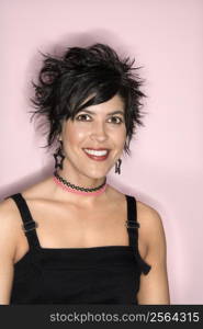 Head and shoulder portrait of smiling Hispanic woman against pink background.