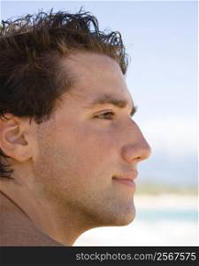 Head and shoulder profile portrait of handsome man on beach.