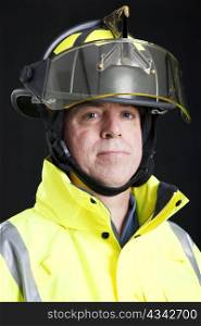 Head and shoulders portrait of a serious firefighter. Studio shot on black background.