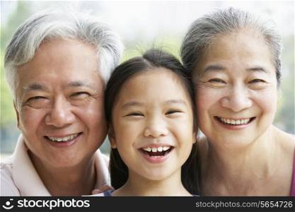 Head And Shoulders Portrait Of Chinese Grandparents With Granddaughter Ride
