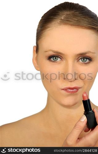 head and shoulders shot of graceful blonde putting on lipstick
