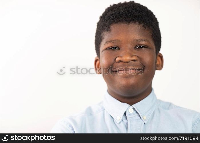 Head and Shoulders Studio Portrait Of Smiling Boy Against White Background