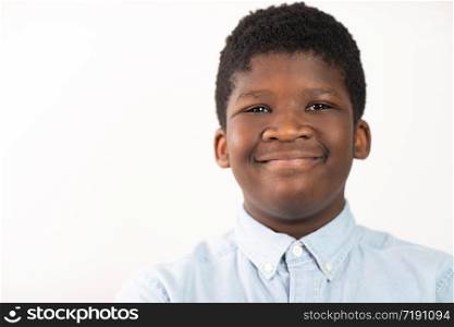 Head and Shoulders Studio Portrait Of Smiling Boy Against White Background