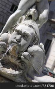 Head carved in stone spits water out of his mouth