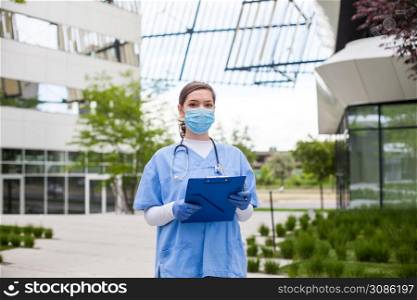 Head of care wearing personal protective equipment holding folder standing in front of nursing home,Coronavirus COVID-19 pandemic outbreak crisis,worried exhausted frontline staff,medical key worker