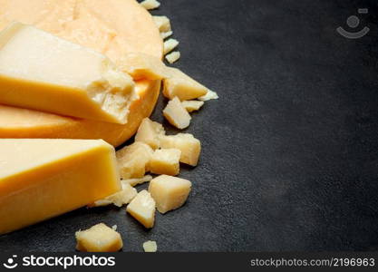 Head of parmesan or parmigiano hard cheese and pieces on concrete background or table. Head of parmesan or parmigiano hard cheese and pieces on concrete background