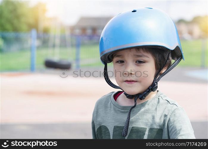 Head shot boy ride a scooter in car park, Child wearing safety helmet riding a roller, Kid playing with his toy outside, Active leisure and outdoor sport for children.