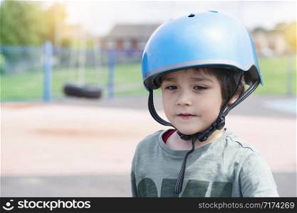 Head shot boy ride a scooter in car park, Child wearing safety helmet riding a roller, Kid playing with his toy outside, Active leisure and outdoor sport for children.