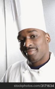 Head shot of African-American male chef wearing traditional uniform and toque looking at viewer.