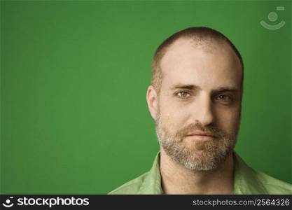 Head shot of Caucasian man with beard and receding hairline against green background.