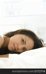 Head shot of Hispanic young adult woman lying on bed.